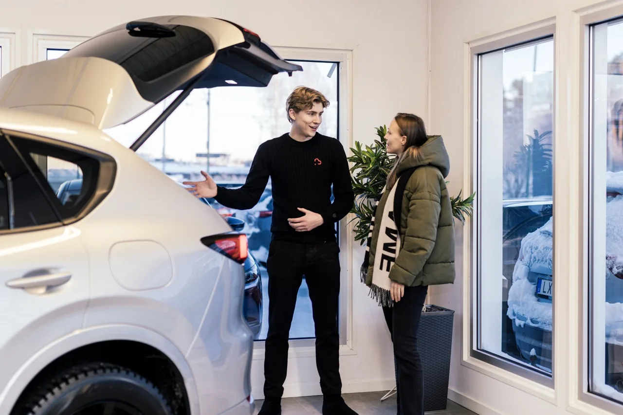 Säljare visar en bil för en kund i bilhallen